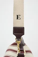 Bolso de mano tipo city, confeccionado en tejido con estampado de rayas verticales en tonos crudo y bordó. Tiene doble correa de hombro extraíble en contraste de tejidos, detalles metálicos y cierre mediante cremallera.