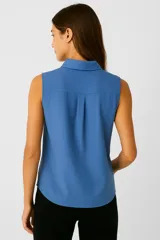 Blusa azul sin mangas de lino con cuello camisero y botones.