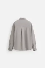 Camisa de hombre relaxed fit con cuello solapa, manga larga con puño abotonado, bolsillo de parche en el pecho y cierre frontal con botones. Diseño a cuadros en tonos gris y blanco.