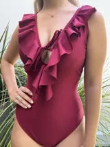 Malla enteriza color borgoña con escote en V y volados en los breteles y en el frente. Se ata en el centro del pecho.