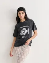 Remera negra con efecto gastado, cuello redondo y estampado frontal con un pez y la leyenda "Mandinga Oriunda del Sur".