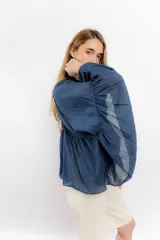 Camisa azul de algodón con cuello alto y mangas largas acampanadas con detalles de puntilla.