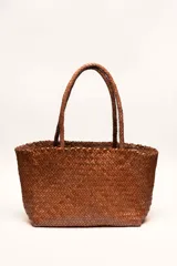 Bolso tote de cuero vacuno color marrón, con diseño trenzado a mano. Tiene doble asa corta trenzada.