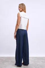 Chaleco blanco con escote en V, detalle de encaje y lazos en el frente.