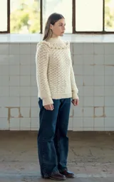 Sweater color crema tejido a crochet con lana merino, cuello alto con volados y mangas largas.