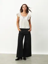 Blusa negra de satén con escote en V y detalle de encaje en el escote.