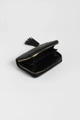 Billetera negra de cuero sintético con diseño capitoneado y tachas doradas. Cierre con cremallera dorada y detalle de borla en el lateral.