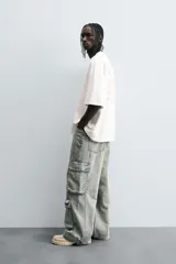 Pantalón relaxed fit de denim negro con efecto lavado, bolsillos frontales, traseros de plastrón y multifunción en perneras. Bajo ajustable con trabilla y cierre frontal con cremallera y botón.