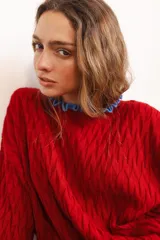 Sweater tejido rojo con cuello alto y puños con volados azules.