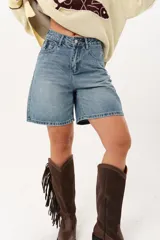 Bermuda de denim celeste con largo por encima de la rodilla, tiro medio, bolsillos delanteros y traseros, y cierre frontal con cremallera y botón.