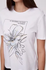 Remera blanca con estampado de hojas de ginkgo biloba en tonos naranja, beige y gris.
