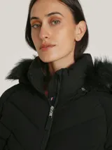 Campera acolchada negra de Tommy Hilfiger con cuello alto forrado en piel sintética, cierre de cremallera, bolsillos laterales y detalles distintivos de la marca.