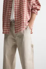 Pantalón color marrón con efecto lavado, corte relaxed fit, cinco bolsillos, aplicación de tira y bolsillo multifunción en perneras, cierre frontal con cremallera y botón.