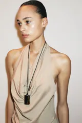 Top color beige confeccionado en algodón 100% con efecto teñido. Presenta cuello halter con lazada y escote drapeado. El bajo tiene un acabado asimétrico.