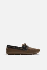 Mocasín casual color marrón fabricado en cuero con acabado serraje, horma redonda, detalle de lazo en el empeine y suela de goma.