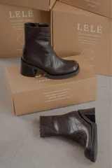 Botas de cuero negro con textura tipo piel de cocodrilo y tacón cuadrado.