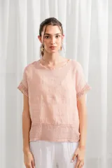 Blusa de lino color rosado, de corte holgado, con cuello redondo y detalle de encaje en ruedo y mangas.