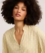 Camisa de viscosa color amarillo pálido con estampado de follaje, cuello mao, cierre frontal con botones y mangas largas con puños ajustados.