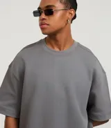 Remera color crema de corte amplio, con cuello redondo y mangas cortas con sisa desplazada. Confeccionada en algodón y poliéster.