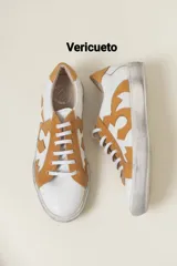 Zapatillas blancas con detalles en color mostaza y diseño gráfico lateral.