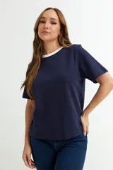 Remera blanca de algodón con cuello redondo y mangas cortas. El cuello es de color azul marino en contraste.