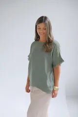 Remera verde musgo de lino italiano, con escote a la base, corte amplio y mangas cortas con detalle desflecado.