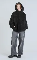 Hoodie negro oversize con cierre central al estilo anorak, confeccionado en piel de corderito sintético. Capucha ajustable con cordón y bolsillo canguro.