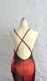 Vestido midi de microtul rojo con estampado de rosas y hojas verdes, escote en V con encaje negro y breteles finos regulables en la espalda.