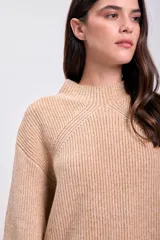 Sweater color beige de punto con cuello alto y mangas ranglan largas. Tejido acanalado vertical.