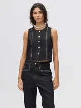 Chaleco corto de denim negro con apliques metálicos y flecos en el ruedo.