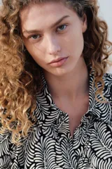 Vestido camisero midi de viscosa con estampado de hojas en blanco y negro, cuello camisero, botonadura frontal y cinturón ancho para atar extraíble. Mangas raglán largas con puños abotonados.