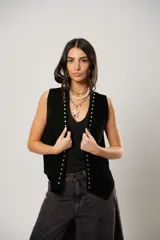 Chaleco negro de cuero descarne con terminación en picos, tachas metálicas y flecos en la espalda.