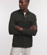 Buzo verde oscuro de media malla acanalada con cuello polo, mangas largas y dos bolsillos delanteros con solapa. Cierre con botones en el cuello.