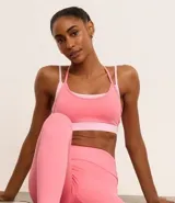 Top deportivo de microfibra color rosa con breteles finos y diseño de superposición bicolor.