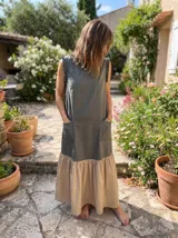 Vestido largo sin mangas, con cuerpo superior color verde militar, falda color beige con volados y bolsillos laterales.