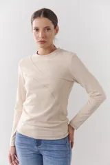 Remera blanca de manga larga con cuello redondo y costuras diagonales en el frente.