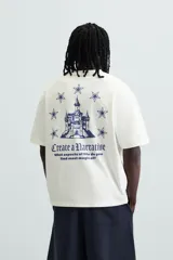 Camiseta blanca de corte holgado con cuello redondo y mangas cortas. Estampa en el pecho con la frase "Create a Narrative" en azul.