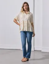 Blusa color crema de crepe con cuello a la base con solapa, escote en V con abertura central y botones. Delantera con detalles plisados y apliques en crochet. Manga corta con terminación fruncida y ruedo en broderie.