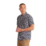 Camisa de manga corta con estampado de flores abstractas en tonos beige sobre fondo azul. Tiene cuello clásico, cierre frontal con botones y bolsillo en el pecho.