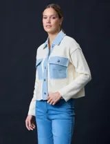 Campera combinada de punto color crema con detalles en denim celeste. Tiene cuello con solapa, cierre frontal con botones metálicos, bolsillos delanteros y corte recto.