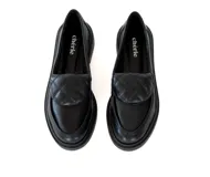 Mocasines negros de cuero con detalle acolchado en la parte delantera y suela plana.