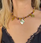 Collar corto de piedras irregulares en tonos borgoña, amarillo y marrón, con dijes de bronce en forma de rombo.