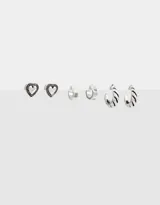 Set de tres pares de aros con pasante bañados en plata. Incluye un par de aros tipo botón con forma de corazón, un par de aros tipo argolla lisa y un par de aros tipo argolla con textura de rayas.