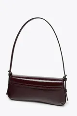 Bolso de hombro color crema con efecto acharolado, solapa con cierre magnético y asa ajustable.
