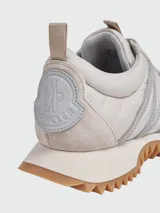 Zapatillas deportivas color beige con detalles en plata y suela de goma.