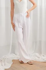 Pantalón de lino blanco, de corte ancho y tiro alto, con cintura elastizada y cordón ajustable.