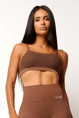Top deportivo marrón con tecnología seamless, calce slim, breteles finos y textura con microtramas respirables. Cuenta con forro interno.