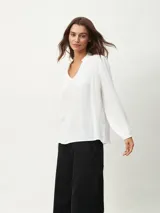 Blusa blanca de manga larga con escote en V y textura arrugada.