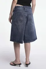 Bermuda de jean azul con lavado ácido, corte ancho y largo a la rodilla.