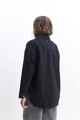 Campera de jean celeste de corte holgado, con cuello camisero, cierre frontal con botones metálicos, mangas largas con puños abotonados, bolsillos frontales con solapa y costuras a la vista.